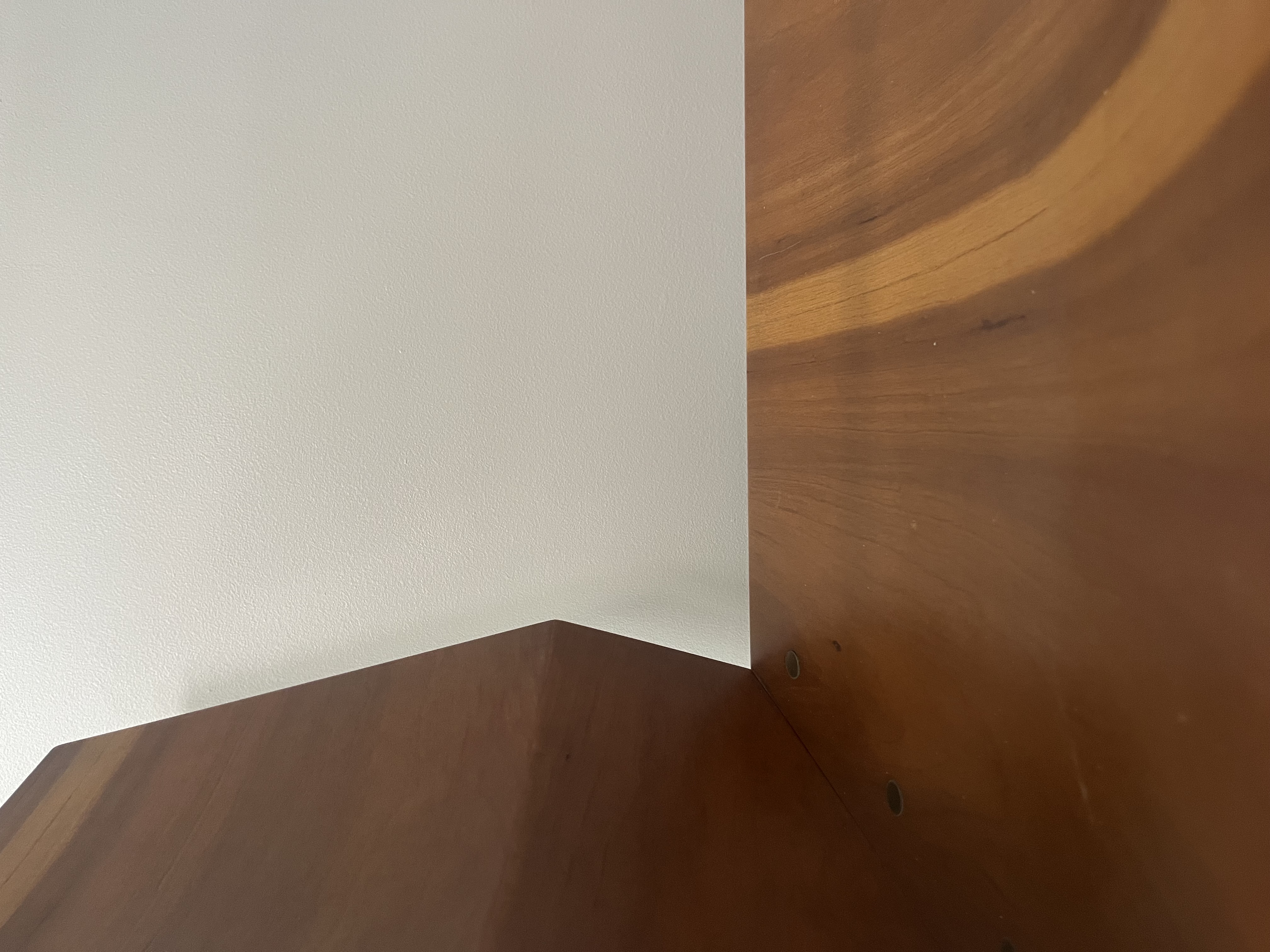 The material is cherry veneer over bent laminated maple, with brass hardware. It is rigid, meaning it does not bend or move easily. The surface looks refined because it is smooth, polished, and shows the natural lines of the wood. The clean edges and shiny finish make it look carefully made and professional.